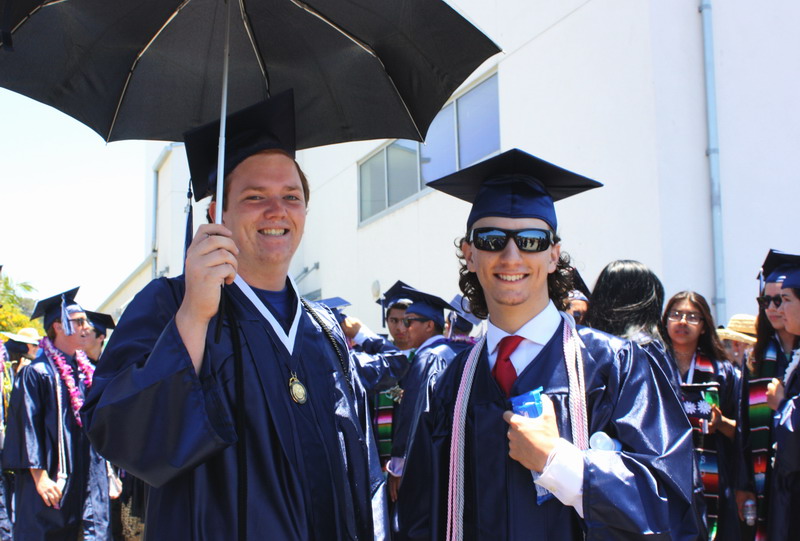 Alumnis Raffi Curtis and Jacob Duga shield themselves from the sun before graduation. Raffi-and-Jacob