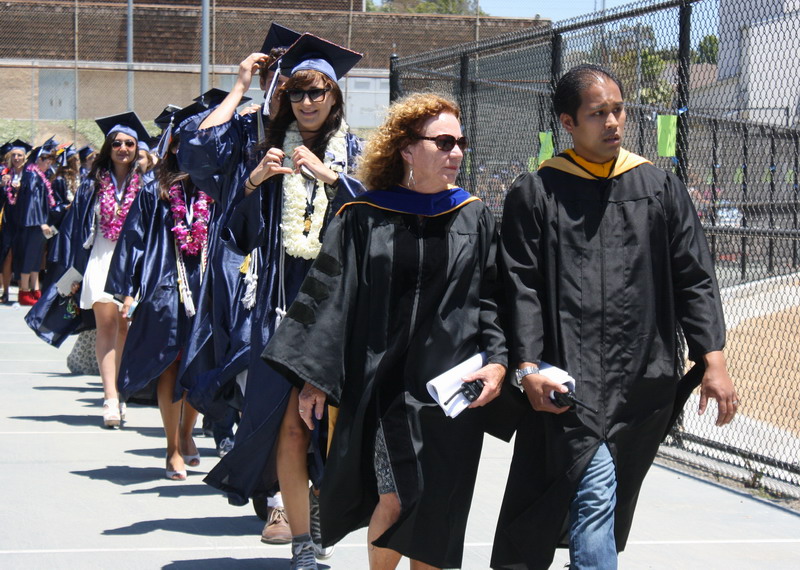 Assistant Principal Jeanne Jones and science teacher Michael Santos walk the first row of seniors out of the tennis courts and to their seats. jones-and-santos