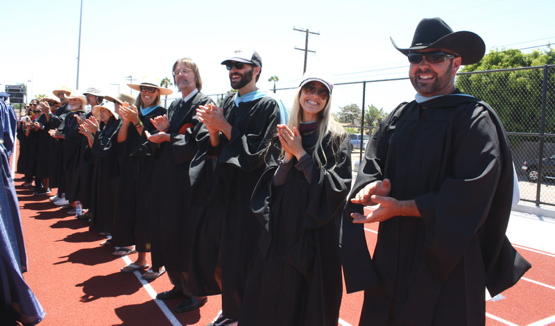 Teachers applaud students as they walk to their seats. teachers