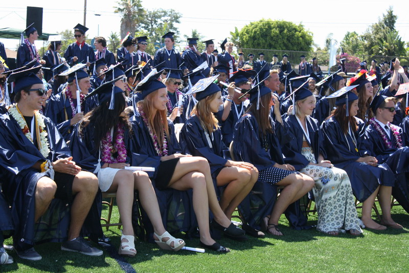Students watch as their classmates receive their diplomas. watching