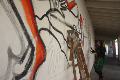 Allyne Powers paints the newest mural next to Senior Court.