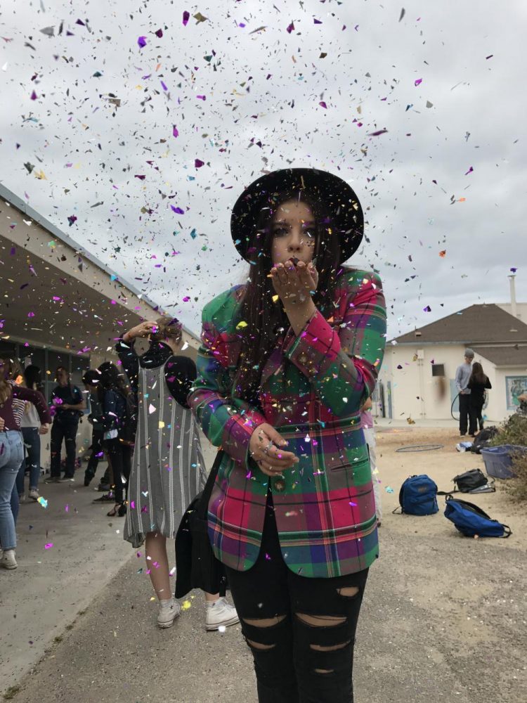 Freshman Mikayla Navatta blows glitter during Exhibition Day.
