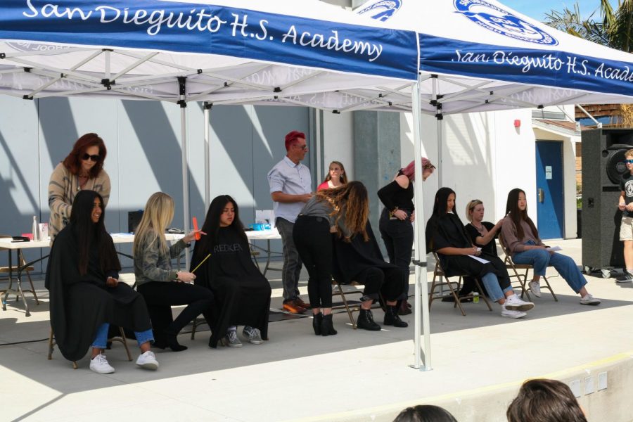 Students lined up in chairs and got their hair put into small ponytails that are easier to cut off. 