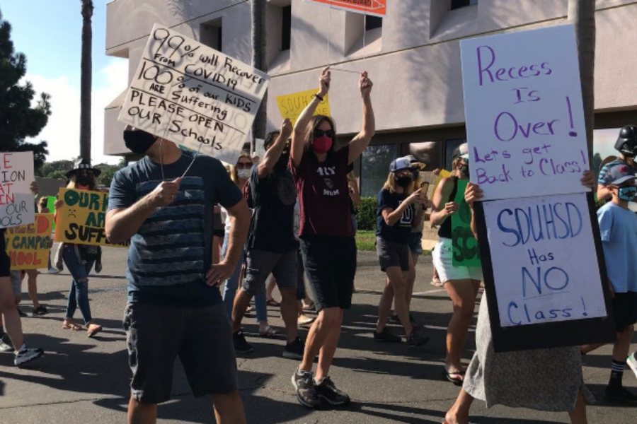 Protestors hold up signs such as Recess Is Over! Lets get Back to Class! SDUHSD Has NO Class! and more in front of the SDUHSD building