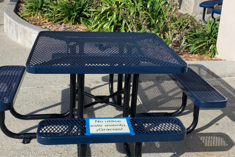 Tables have signs that tell students not to sit in certain spots near the Mustang Commons and around campus