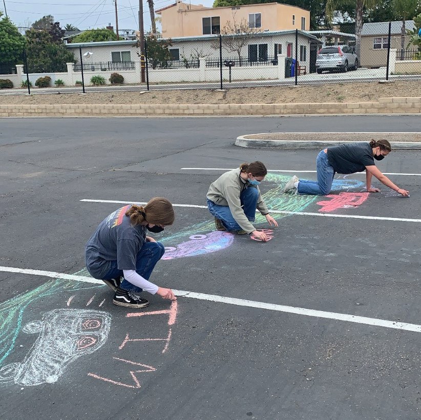 Three girls in a row drawing with chalk