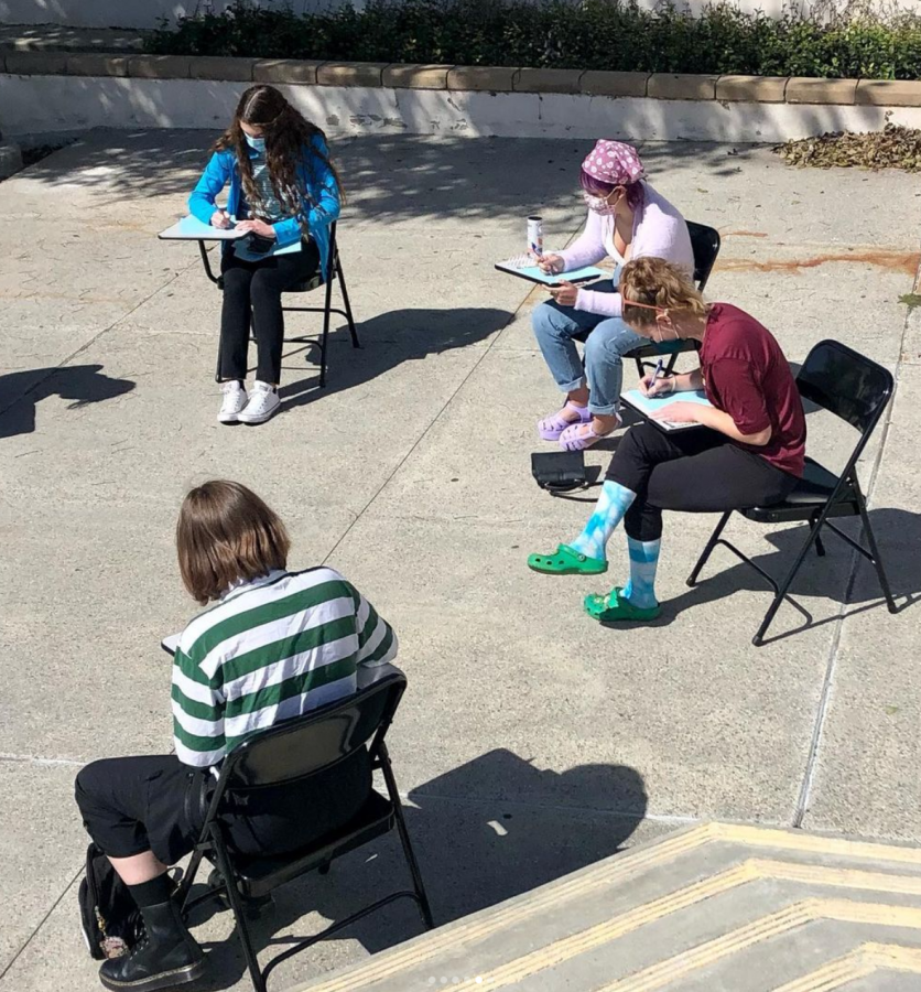 Four girls sitting in a school chair desk writing