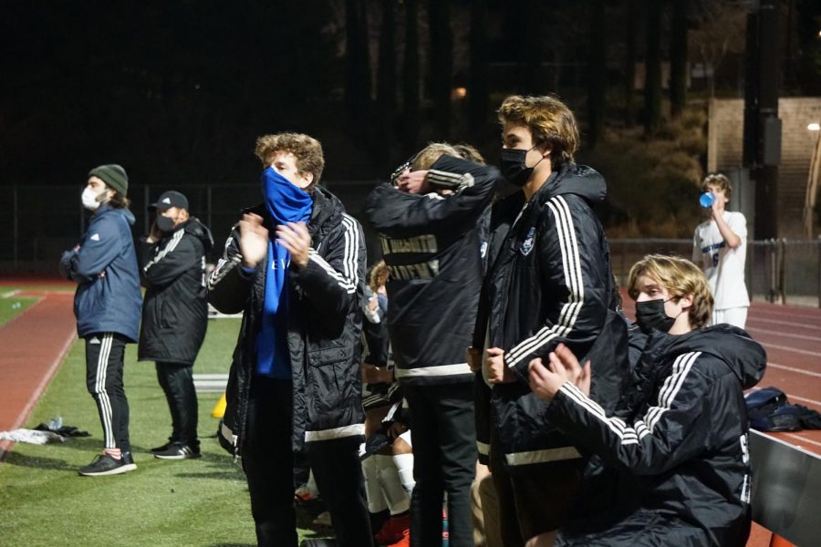 three boys watching the soccer game in a stadium with a blue mask and black masks