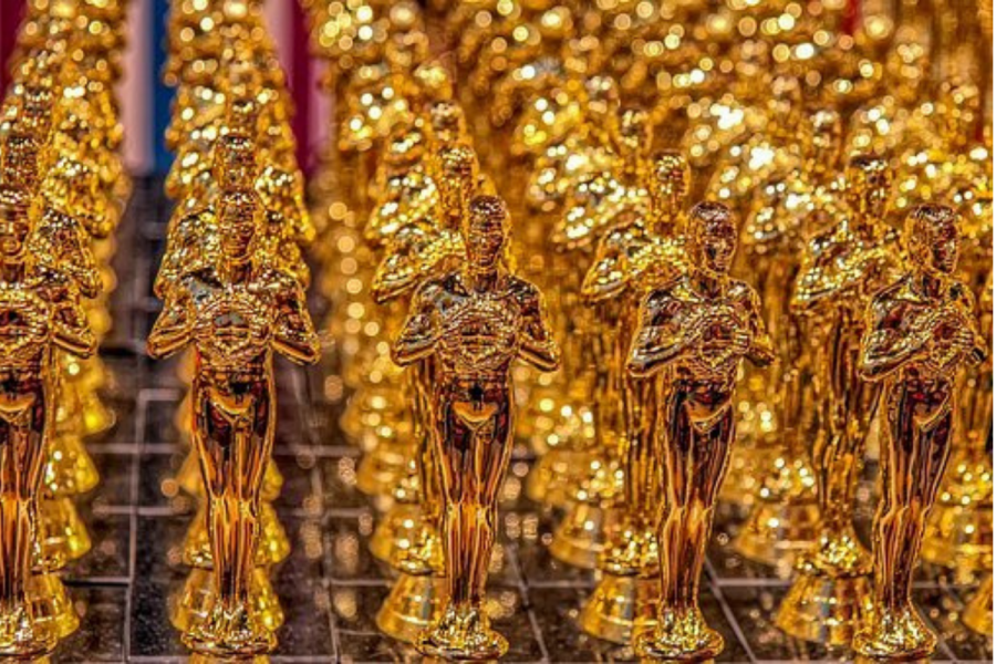 Image of many golden Oscars awards lined up together.