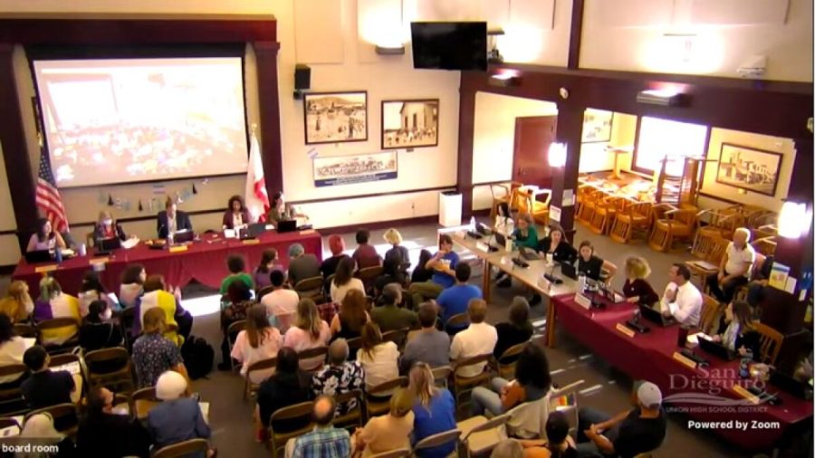 A crowd of students and parents sits in lines of chairs in the SDA learning commons. They are facing the board, and are sitting next to the School Board Representatives and other officials. Many are facing the school board representatives.